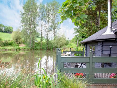a house with a fence next to a river at Mallard Roundhouse - Uk33891 in Cullompton