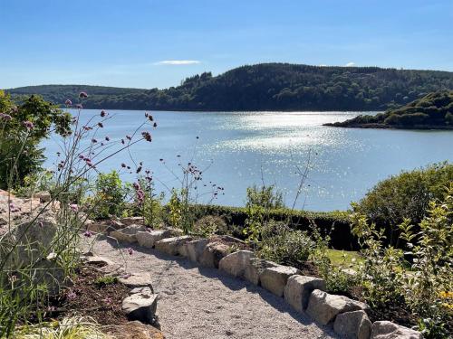 a stone path next to a lake with trees at Berkeley in Kippford