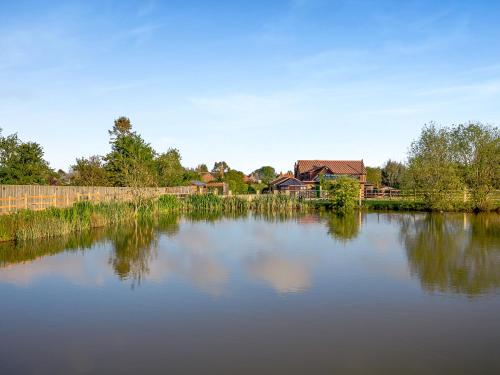 a large body of water with a house in the background at Clay Lake Cottages - Dad's Shed in Covenham