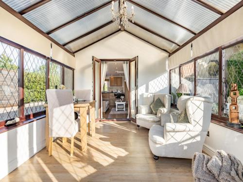 a living room with a table and chairs and windows at Clay Lake Cottages - Dad's Shed in Covenham