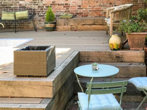 a patio with a table and chairs and stairs at Yew Tree House Cottage in New Romney