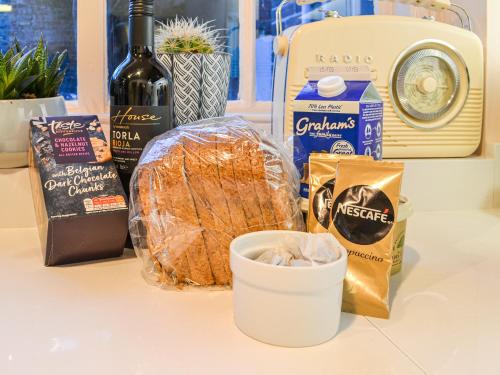 a counter topped with bread and a bottle of wine at Yew Tree House Cottage in New Romney