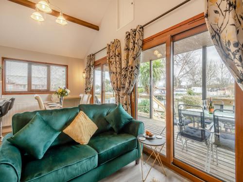 a living room with a green couch and a balcony at River Retreat-B6842 in Brundall
