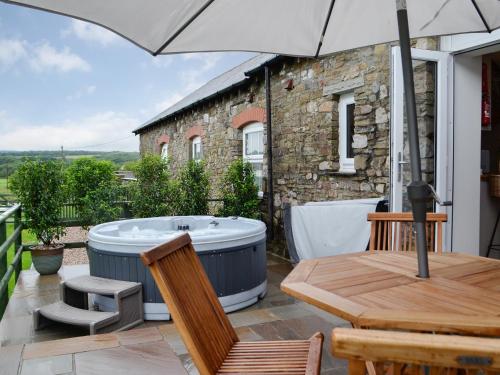a hot tub on the patio of a house at Sgubor Llwyndu in Bettws
