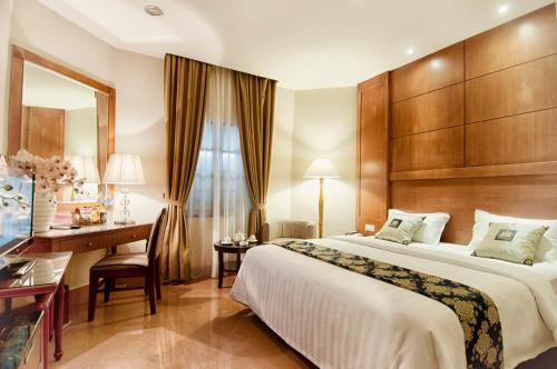 a hotel room with a bed and a desk at Grand Sakura Hotel in Medan