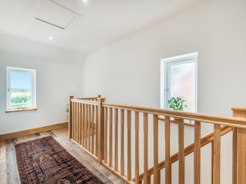 a wooden staircase in a room with two windows at Dragonfly Den - Uk44530 in Horncastle