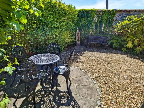 a patio with a table and chairs and a bench at Bockety Barn in Stalham