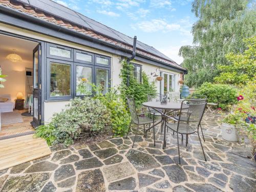 a patio with a table and chairs in front of a house at The Granary Store in Woodrising