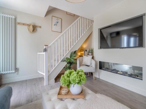 a living room with a staircase with a large tv at Ty Mor in Abersoch