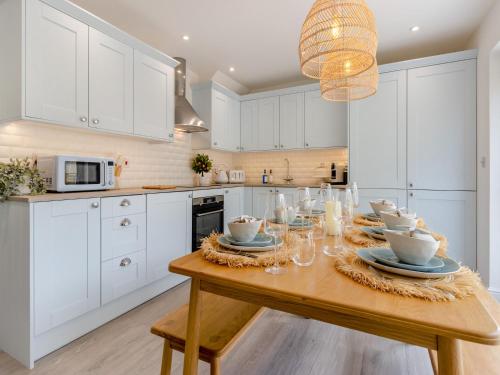 a kitchen with white cabinets and a wooden table at Ty Mor in Abersoch
