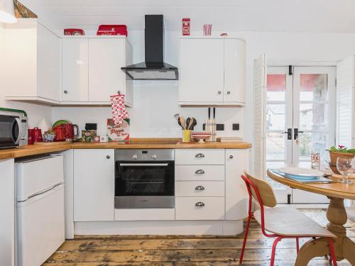 a kitchen with white cabinets and a table at Ty Macsen in Llanwnda