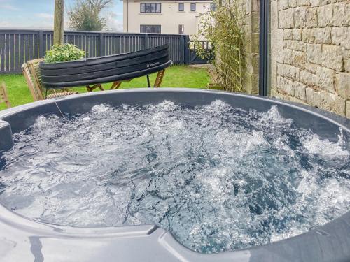 a hot tub filled with water in a yard at Whitehill Barn - Uk47195 in Kirkcambeck
