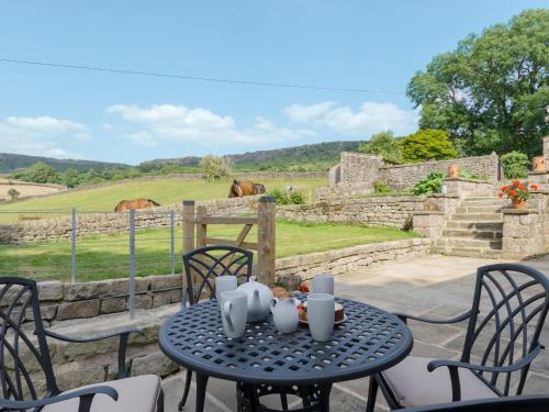 a table and chairs with a view of a field at The Barn At Grislow Field in Curbar