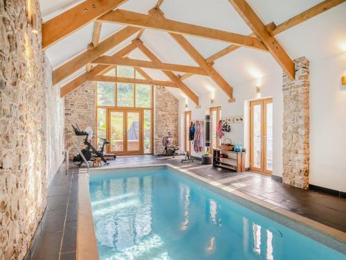 an indoor pool in a house with wooden beams at Carreg Gwenlais Barn in Carmel