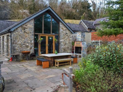 a stone house with a table in the yard at Carreg Gwenlais Barn in Carmel