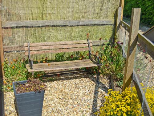 a wooden bench in a garden with flowers at The Hayloft - Ukc1038 in Hickling