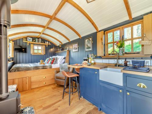 a kitchen with blue cabinets and a bed in the background at Flossys Hut - Uk43675 in Haworth