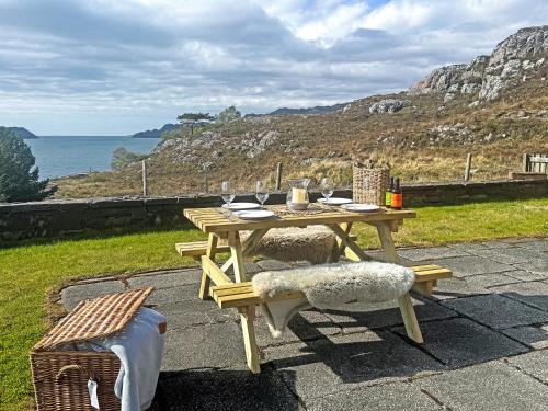 a wooden picnic table with two chairs and the ocean at Rubha Lodge in Shieldaig