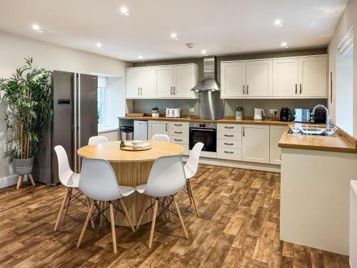 a kitchen with a wooden table and white chairs at Darris Farmhouse in Lochend