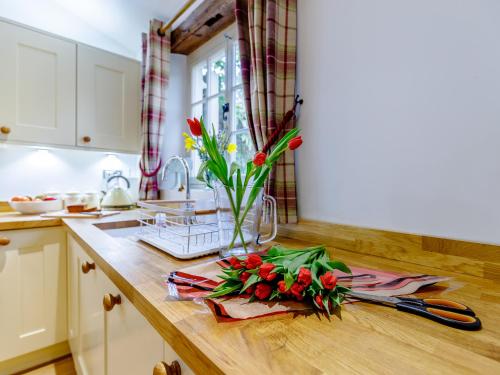 a kitchen counter with flowers in a vase on it at Kilcot Coach House in Hillsley