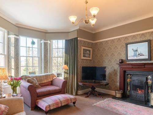 a living room with a couch and a tv and a fireplace at Orrest Howe in Windermere