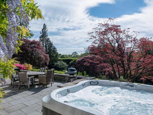 a jacuzzi tub in a garden with a table and chairs at Orrest Howe in Windermere