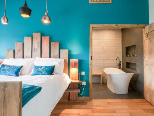 a bedroom with a large bed and a bath tub and a tub at The Pendre Longbarn in Pentre-briwnant