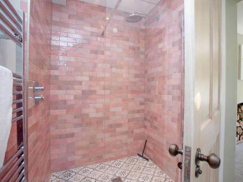 a bathroom with a shower with a red brick wall at The Pink House in Branscombe