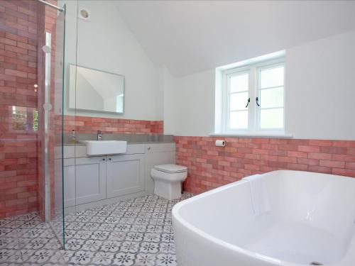 a bathroom with a tub and a sink and a toilet at The Pink House in Branscombe