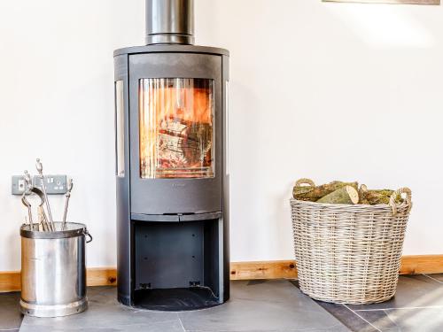 a stove with a fire in a room with a basket at Y Glowty Newydd - Uk31701 in Llandissilio