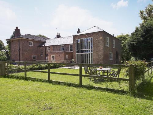 a fence with a table in front of a house at Curlew Barn in Sutton Bridge