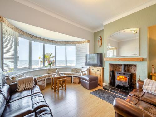 a living room with a couch and a fireplace at Waterside in Llandrillo-yn-Rhôs