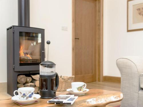 a coffee maker on a table in front of a fireplace at The Old Dairy-Ukc2112 in Royal Wootton Bassett