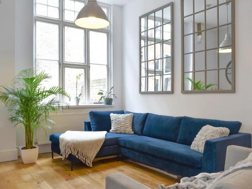 a living room with a blue couch and two windows at Old Parish Hall in Ramsgate