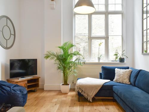 a living room with a blue couch and a tv at Old Parish Hall in Ramsgate