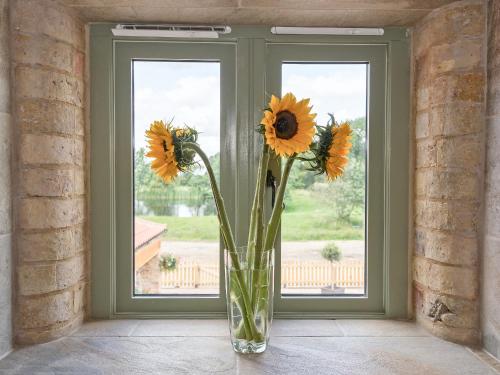 a vase filled with sunflowers sitting in a window at Eastlands Barn in East Barkwith
