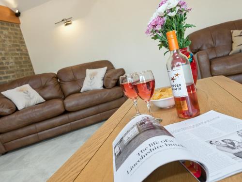 a table with a bottle of wine and a glass at Eastlands Barn in East Barkwith