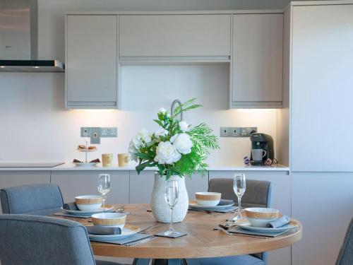 a dining room table with a vase of flowers on it at Soft Sands - Cottage in Woolacombe
