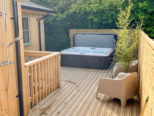 a hot tub on a wooden deck with a chair at Hobby Lodge in Saint Columb Major