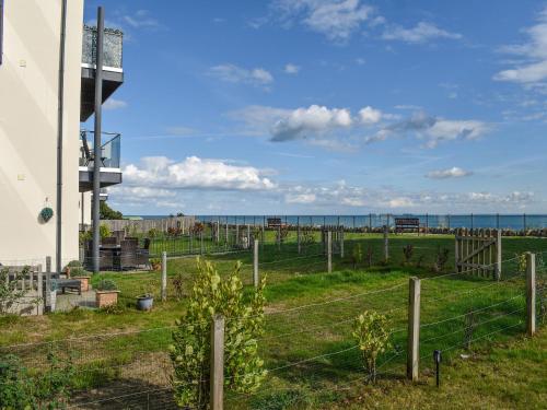 a fence in front of a field with the ocean in the background at Seascape in Sandown