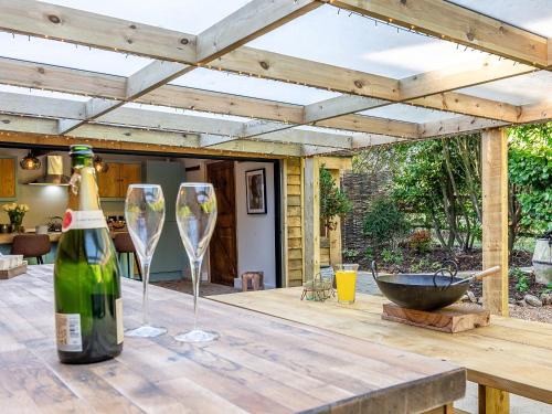 a bottle of wine and two wine glasses on a wooden table at Old Shires Barn in Norton