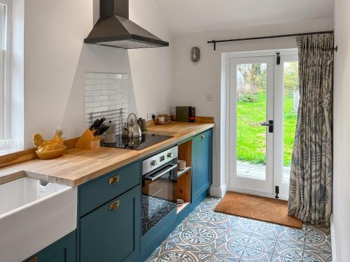 a kitchen with blue cabinets and an open door at The Cowshed - Uk50803 in Cratfield