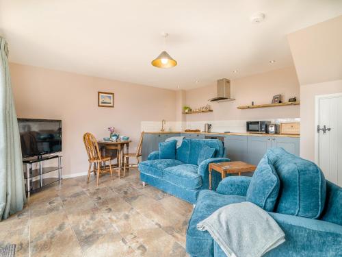 a living room with two blue couches and a kitchen at The Old Stable At Henley View in Draycott