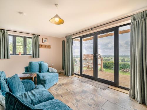 a living room with two blue chairs and sliding glass doors at The Old Stable At Henley View in Draycott