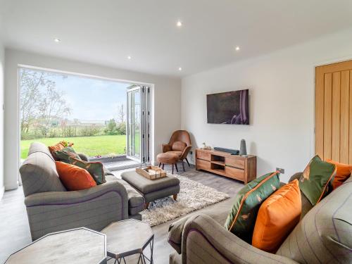a living room with couches and a large window at Longridge in Peldon