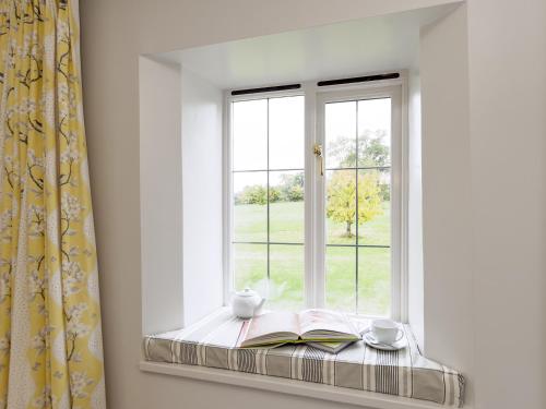 a window seat with books and cups and a book at The Row in Much Marcle