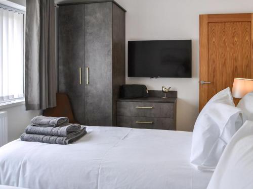 a bedroom with a white bed with a television on it at Linden Manor in Bridlington