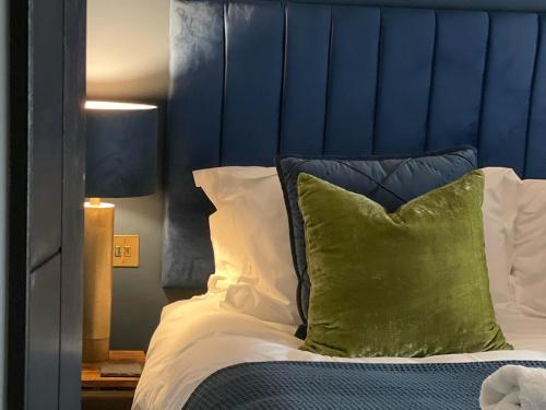 a bed with a blue headboard and a green pillow at Millgate Fosse Cottage in Richmond