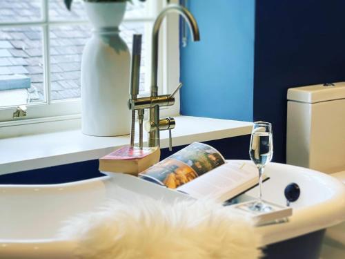 a bathroom sink with a glass of wine and a bottle at Millgate Fosse Cottage in Richmond