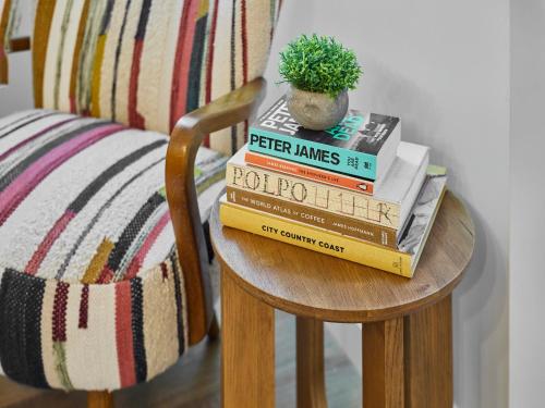 a stack of books on a chair with a potted plant at Hovera Cottage in Windermere